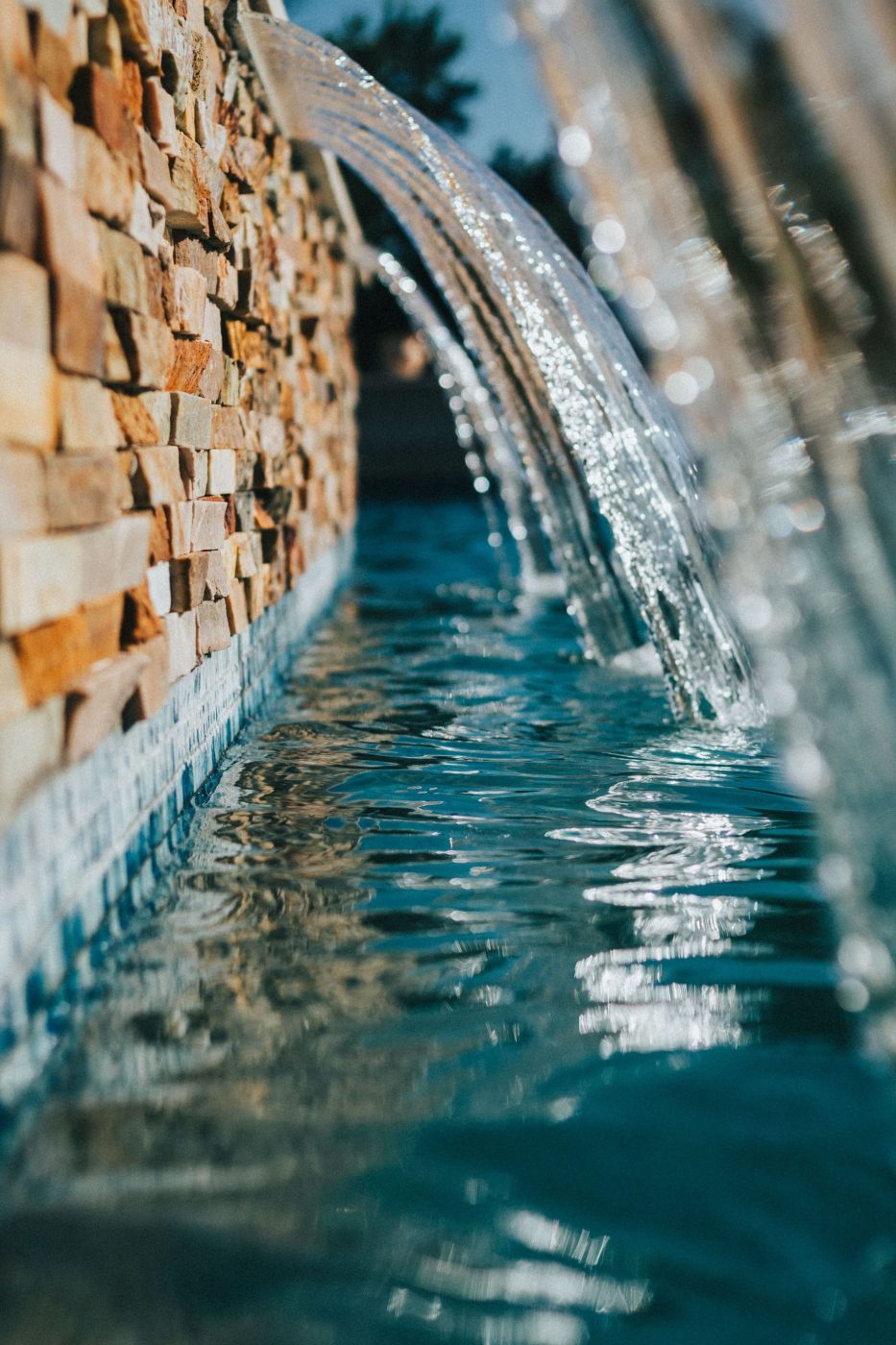 Detalle de cascada de piedra natural en piscina de obra en Alicante