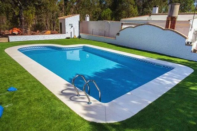 Una gran piscina rodeada de césped y árboles.